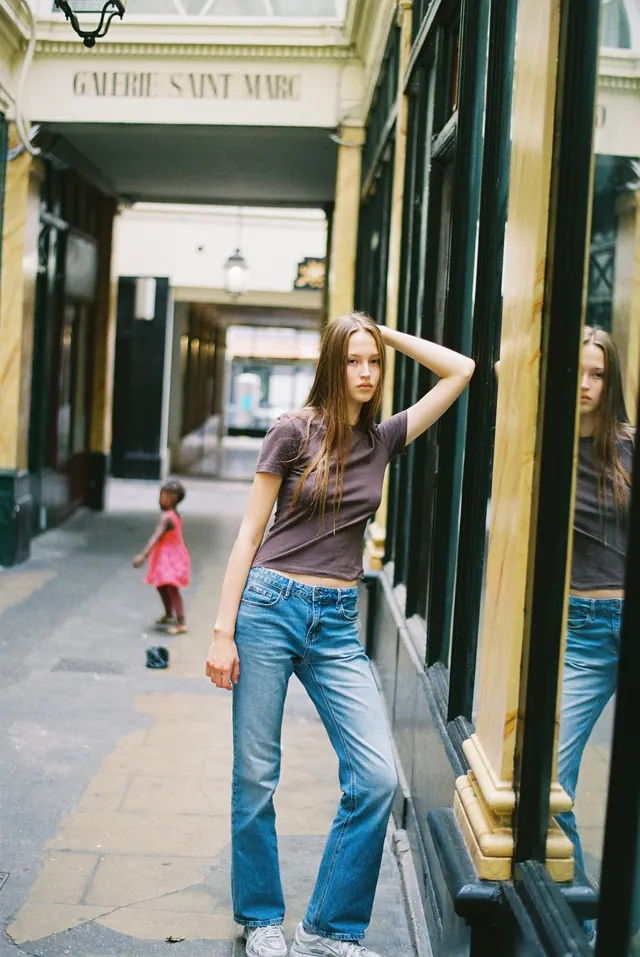 Full-length portrait in a glass-fronted covered passage.