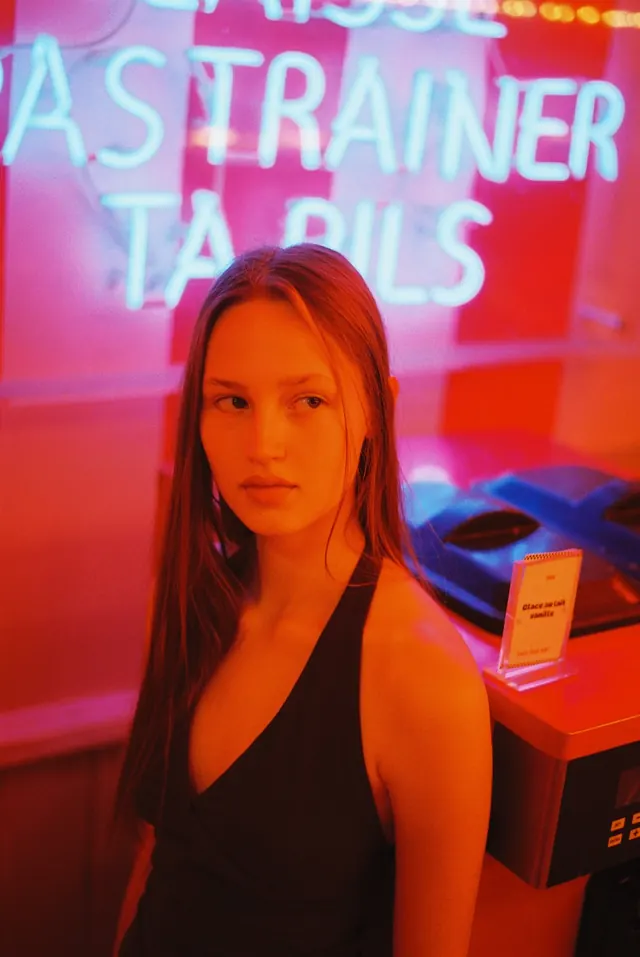 Portrait lit by saturated orange and pink neon.