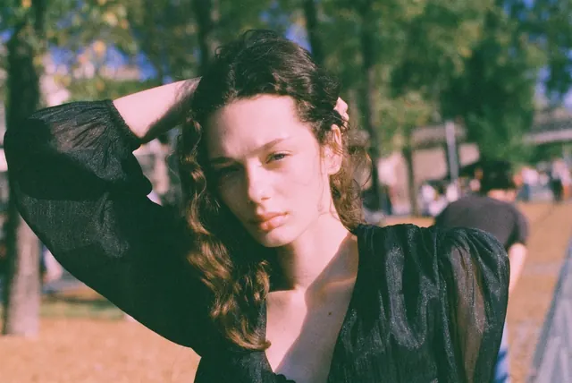 Horizontal close portrait outdoors with one arm behind the head.