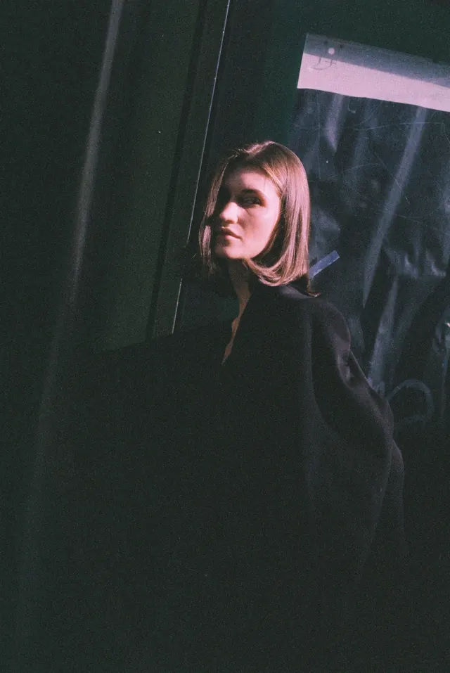 Portrait in a dark doorway, with a narrow shaft of light across the face.